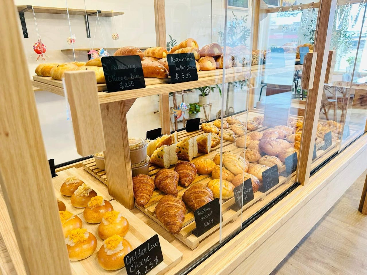 Home An inviting bakery showcasing a variety of fresh pastries and breads displayed in wooden shelves.